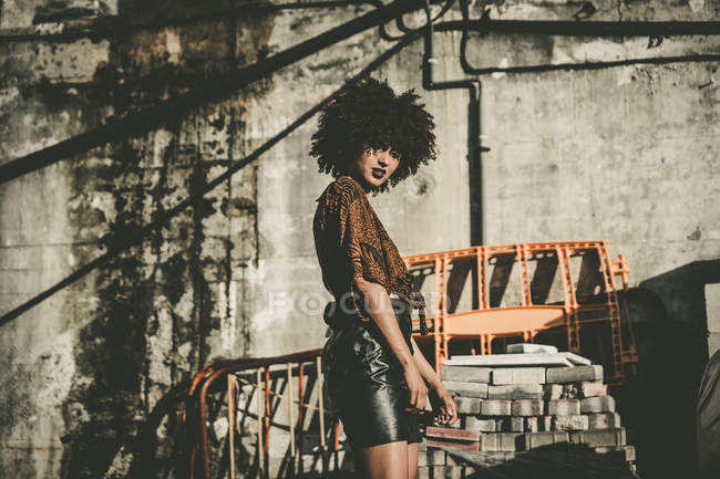 Girl in shirt and leather skirt posing at construction plant — Stock Photo