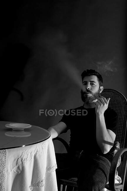 Retrato del hombre fumando en una habitación oscura - foto de stock
