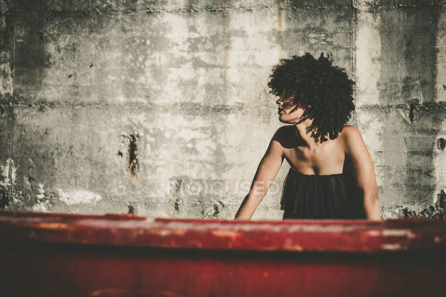 Girl with curly hair leaning on red construction and looking away — Stock Photo