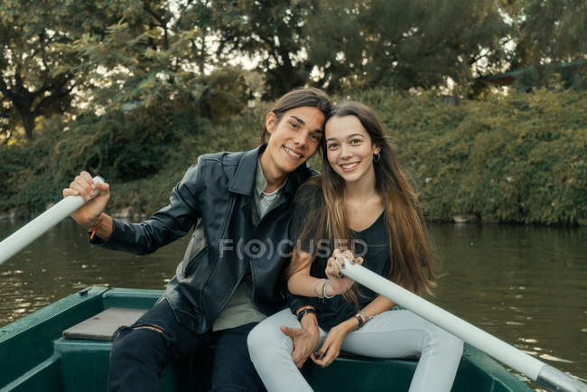 Porträt eines jungen Paares, das im Boot sitzt und in die Kamera am Parksee blickt — Stockfoto