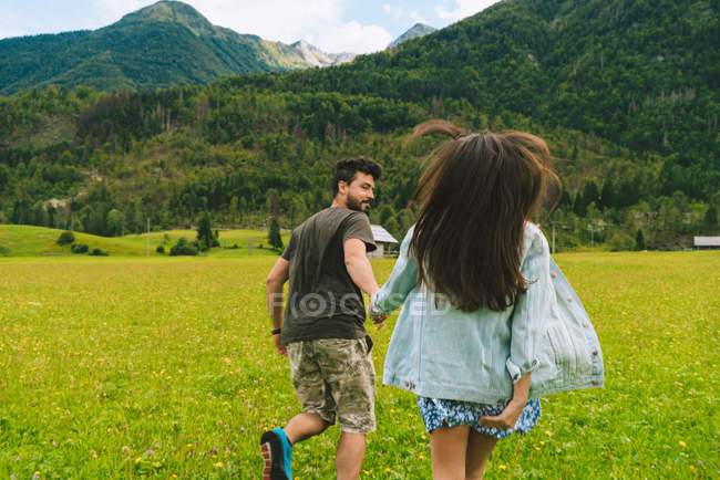 Casal correndo no prado em colinas — Fotografia de Stock
