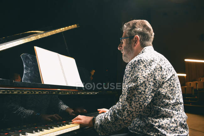 Вид сбоку пожилого человека, играющего на фортепиано — стоковое фото