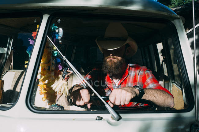 Portrait of anonymous bearded man behind wind screen and holding steering wheel — Stock Photo