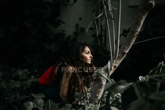 Side view of brunette girl posing at plants — Stock Photo