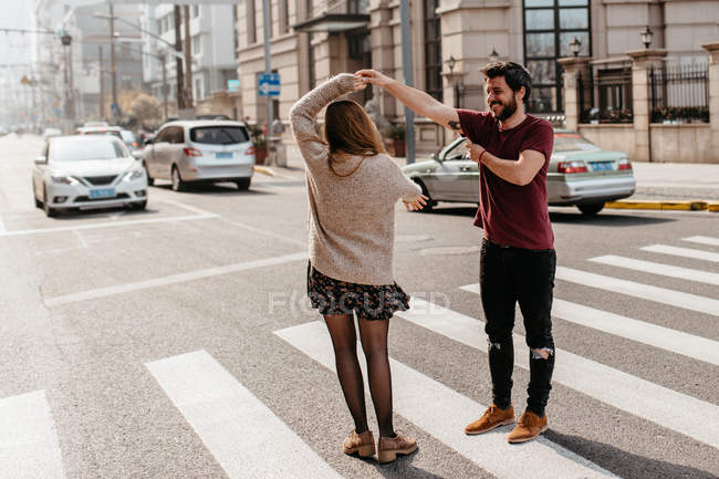Young cheerful couple dancing on pedestrian crossing. — Stock Photo