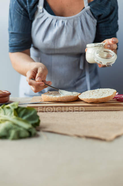 Cook spreading sauce on bun — Stock Photo