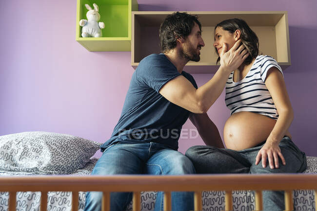 Casal bonito beijando no quarto do bebê. — Fotografia de Stock