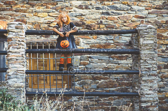 Girl with pumpkin basket posing on fence — Stock Photo