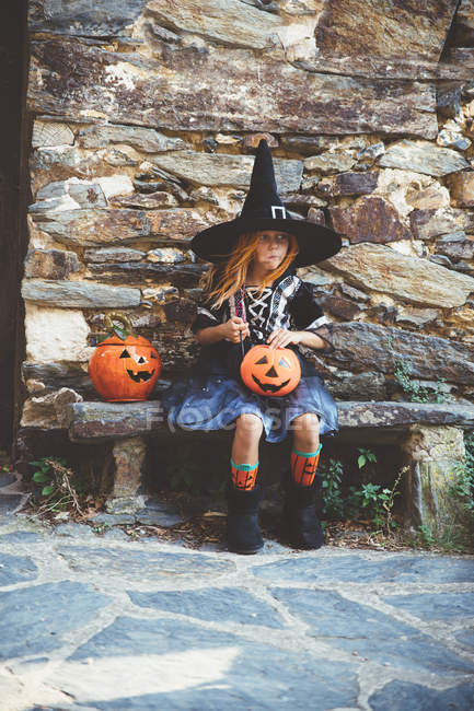 Ragazza in costume da strega seduta sulla panchina — Foto stock