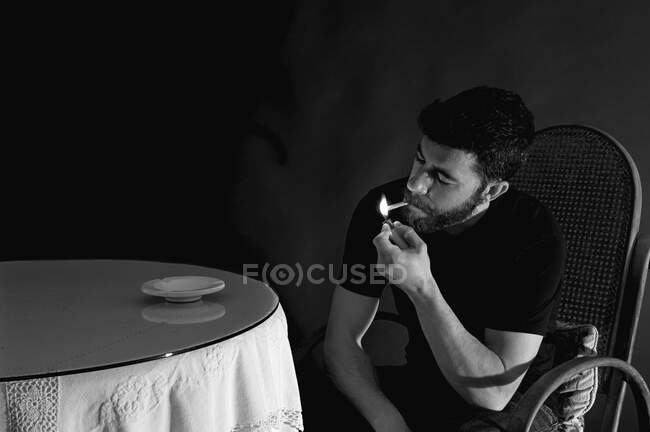Портрет человека, курящего в темной комнате — стоковое фото