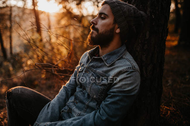 Jovem descansando em madeiras de outono iluminadas pelo sol — Fotografia de Stock