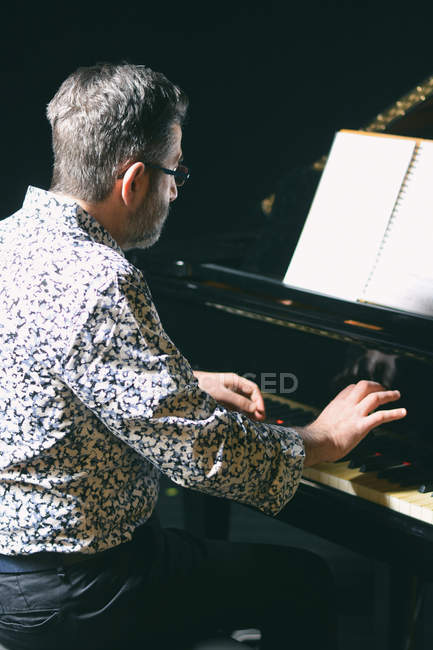 Senior man in glasses playing piano — Stock Photo
