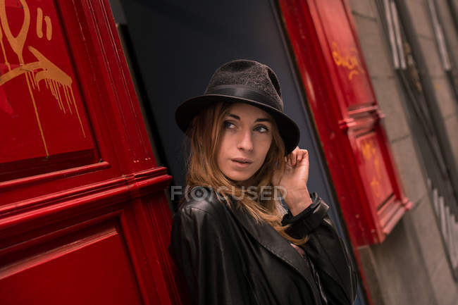 Chica joven con sombrero mirando por la puerta - foto de stock