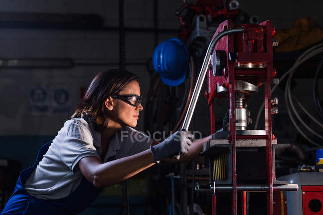 Side view of female mechanic operating hydraulic press — Stock Photo