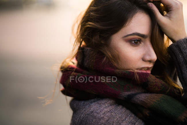 Portrait of young woman standing in warm clothes and touching face. — Stock Photo