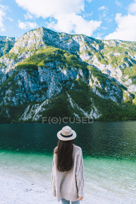 Ragazza in cappello in piedi sulla riva del lago — Foto stock