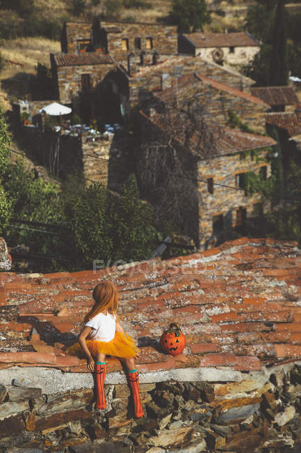 Girl in costume looking over shoulder on roof — Stock Photo