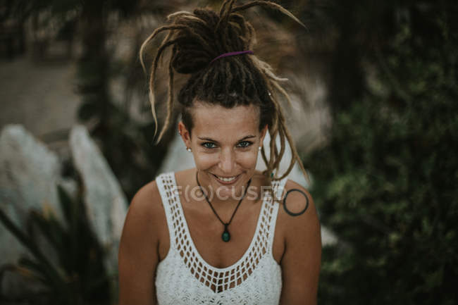 Portrait grand angle de femme souriante avec dreadlocks regardant la caméra — Photo de stock