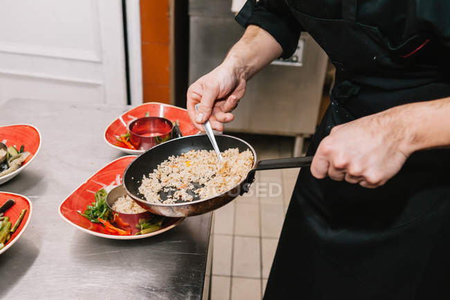 Mid section of cook serving dishes at restaurant kitchen — Stock Photo
