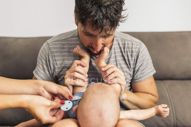 Portrait of loving father with baby lying on his legs playing with his feet — Stock Photo
