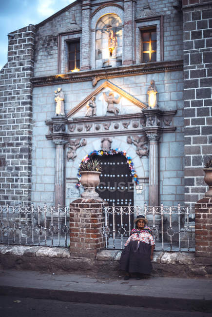 AYACUCHO, PERU - 30 ДЕКАБРЯ 2016: Старуха сидит у церковного забора на улице и смотрит в сторону — стоковое фото