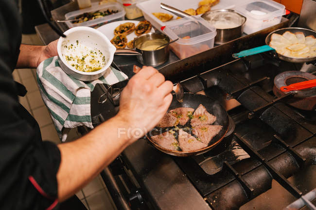 Vista de alto ângulo do chef adicionando ingredientes na panela no fogão — Fotografia de Stock