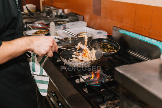 Vista ravvicinata delle mani dello chef che cucinano il piatto sulla padella nella cucina del ristorante — Foto stock