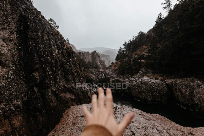 Crop male hand reaching out toward mountains — Stock Photo