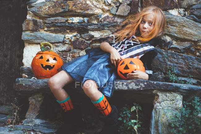 Girl in witch costume on bench — Stock Photo