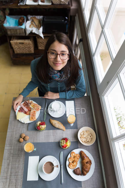 Портрет брюнетки в очках, сидящей за завтраком и смотрящей в камеру — стоковое фото