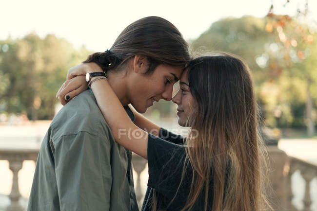 Retrato de jovem casal abraçando cara a cara no parque — Fotografia de Stock