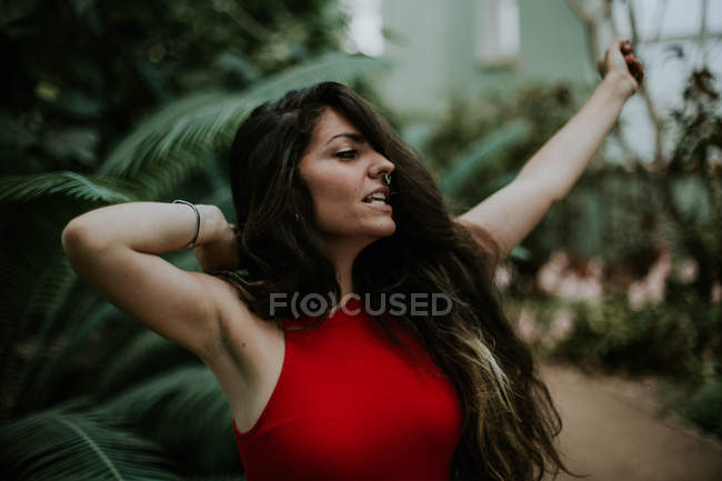 Porträt eines fröhlichen brünetten Mädchens, das im botanischen Garten posiert — Stockfoto