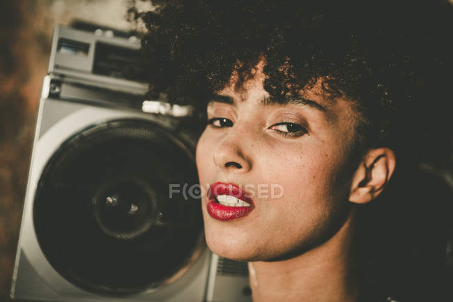 Expressive girl with curly hair posing by vintage tape player — Stock Photo