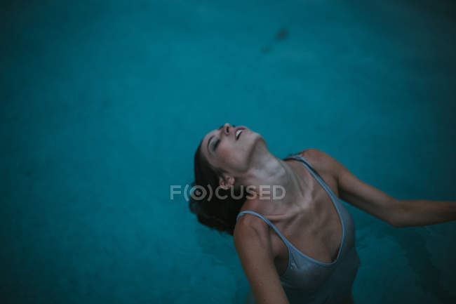 Портрет женщины в мокрой майке, сгибающей шею в бассейне — стоковое фото