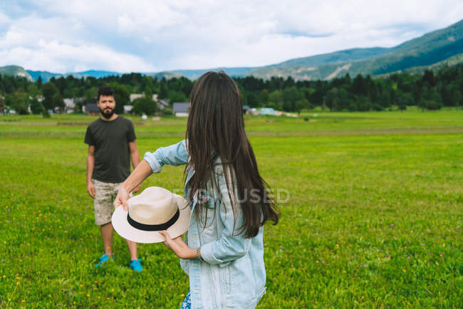 Donna che lancia cappello all'uomo sul prato — Foto stock