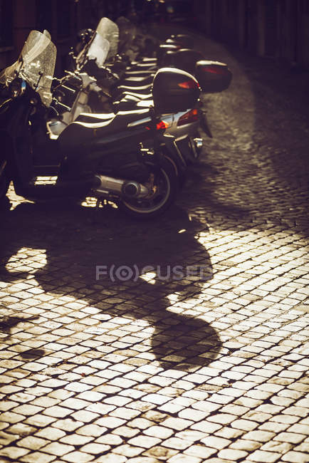 Fila de scooters aparcados en la escena de la calle al atardecer - foto de stock