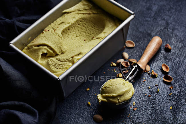 Natureza morta do recipiente com sorvete de pistache e colher — Fotografia de Stock
