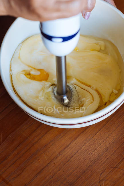Crop mão batendo ovos com liquidificador de mão em tigela — Fotografia de Stock