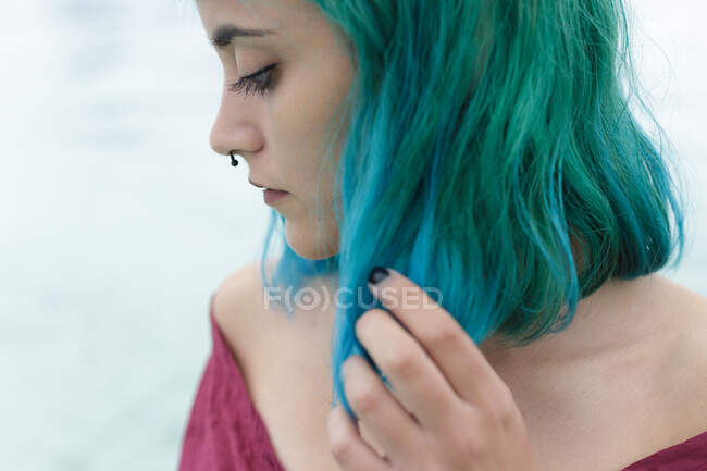 Vista de cerca de la triste chica de pelo azul mirando hacia abajo y tocándose el pelo. - foto de stock