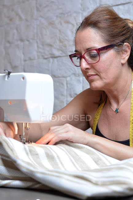 Female tailor thoughtfully sewing with machine — Stock Photo