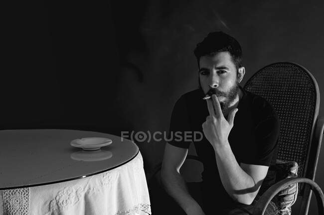 Retrato del hombre fumando en una habitación oscura - foto de stock
