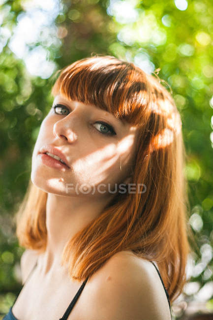 Портрет рыжеволосой девушки, смотрящей в камеру над зеленью — стоковое фото