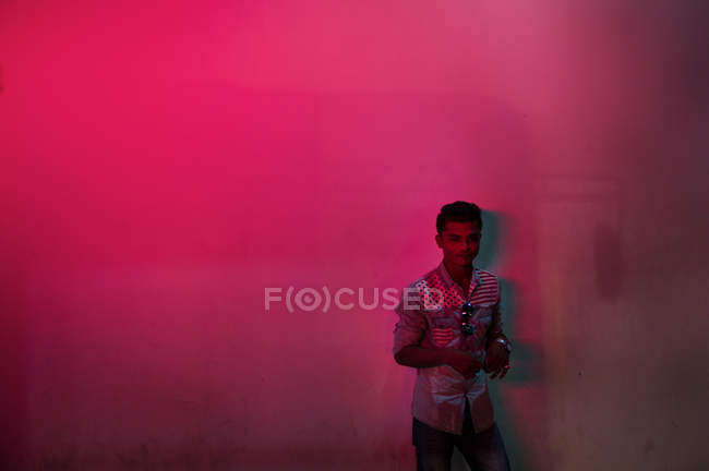 KAULA LUMPUR, MALASIA - 26 MART, 2016: Молодой человек в рубашке позирует на заднем плане стены в неоновом свете . — стоковое фото