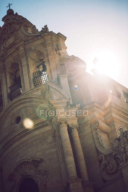 Fachada de iglesia adornada sobre rayos de sol brillantes - foto de stock
