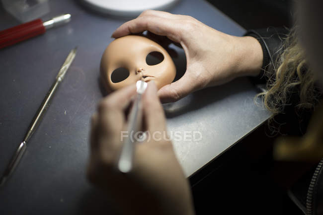 Crop doll maker's hands modeling doll face at table — Stock Photo