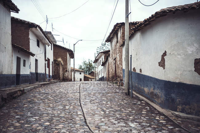Calle pavimentada con fachada rural de casas de pueblo - foto de stock