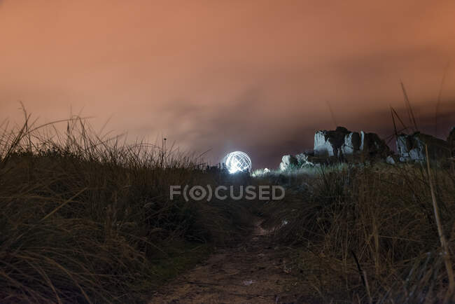 Noche pintando una esfera luminosa en el hil - foto de stock
