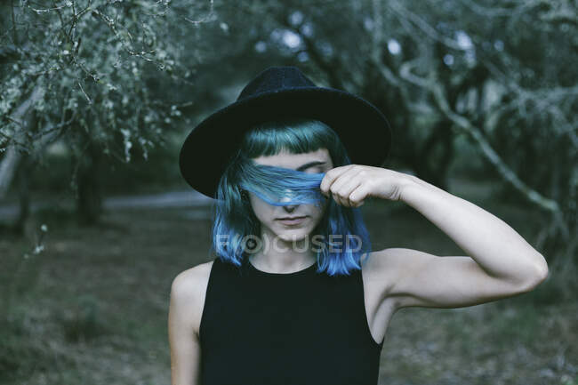 Крупним планом портрет красивої дівчини, що тримає блакитне волосся перед її закритими очима . — стокове фото