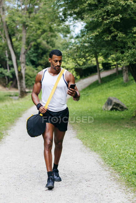 Fit man walking with smartphone — Stock Photo