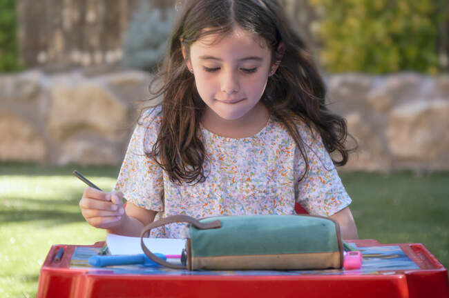 Bambina che studia in giardino una giornata estiva soleggiata — Foto stock